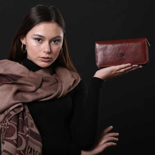 Woman holding a Tony Perotti dark brown leather zip wallet  against a dark background