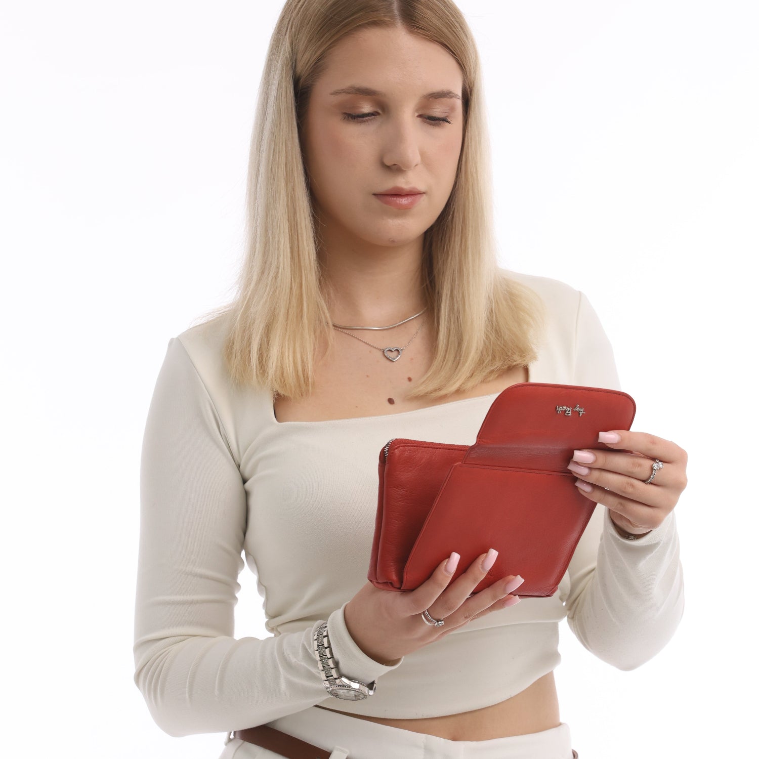 Woman looking into the built-in mirror of a Tony Perotti red leather cosmetic bag