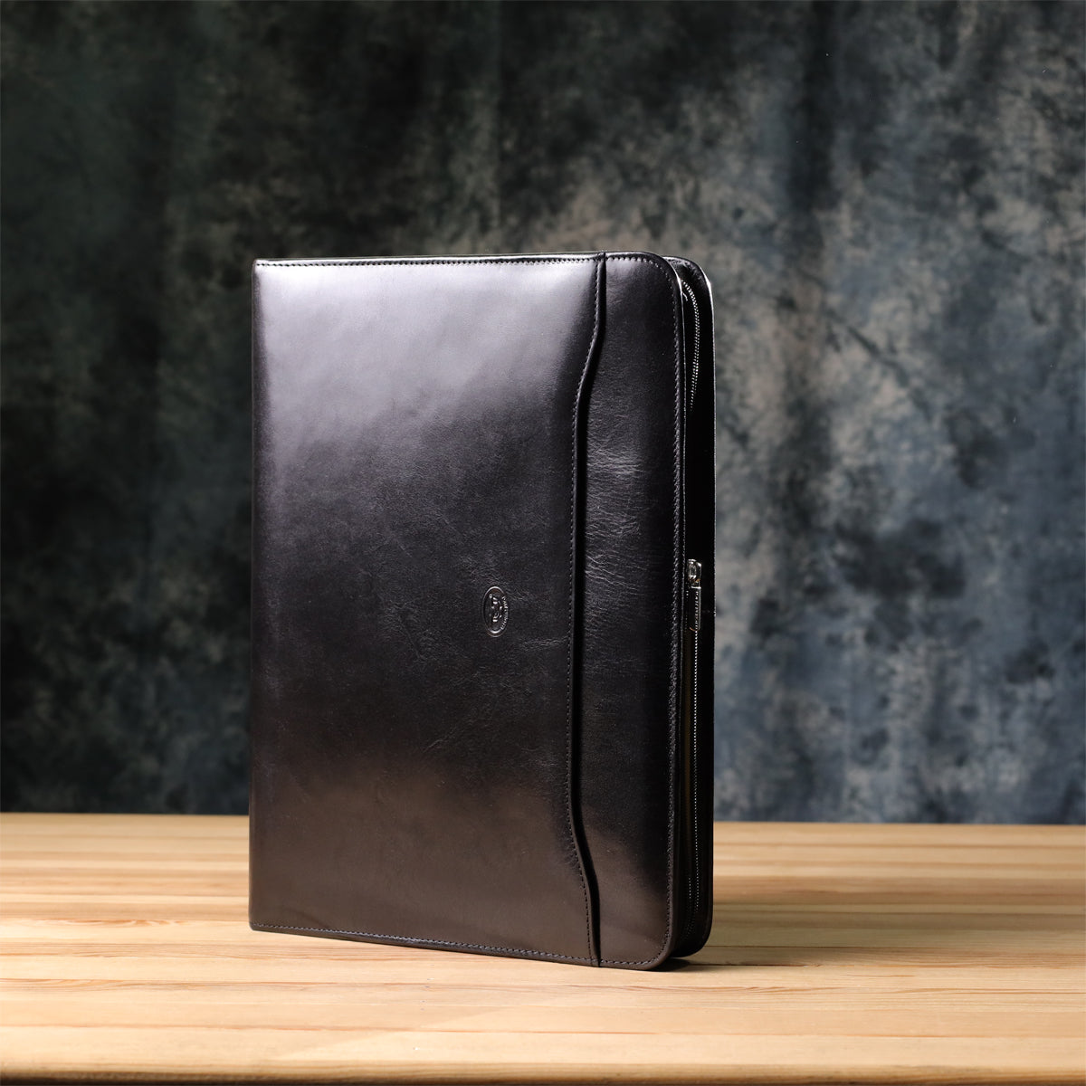 Black Tony Perotti Italico 1278L padfolio handcrafted in Italy standing on a wooden desk — front with the embossed turtle emblem