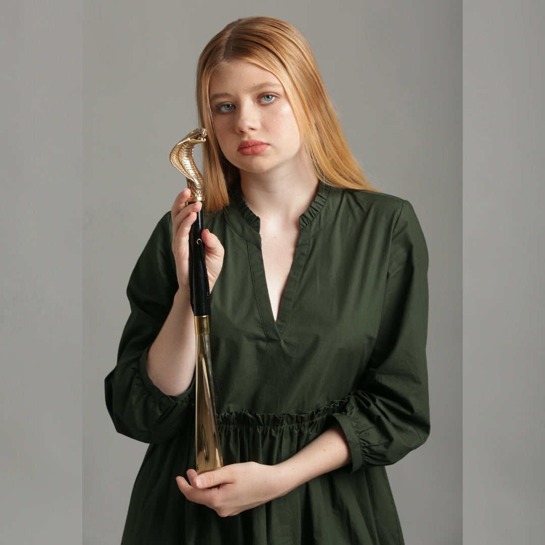 Model standing and holding the Pasotti shoehorn with a gold-colored cobra handle