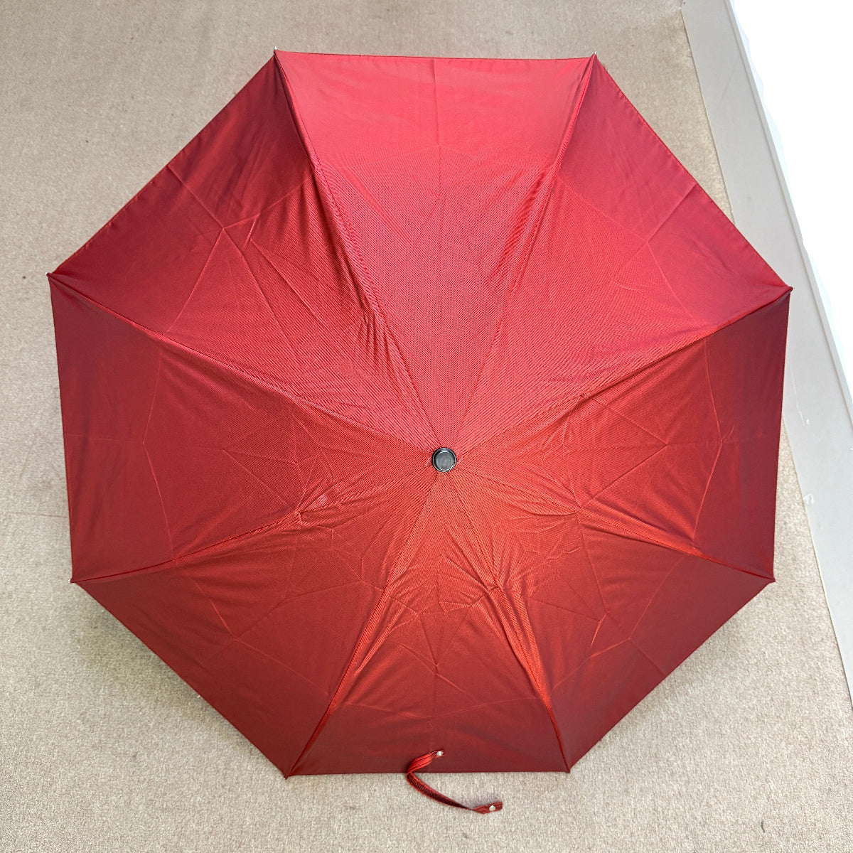 Luxury handmade Pasotti red folding umbrella on a light-colored floor