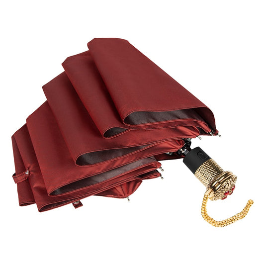 Folded red umbrella with a gold handle on a white background