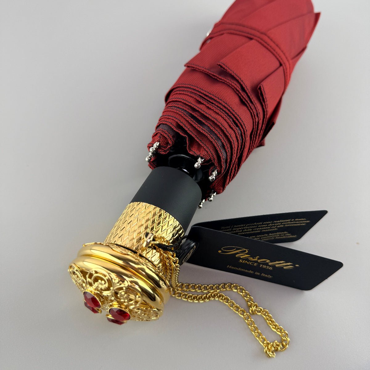 Pasotti foldable red umbrella with gold handle on a white background