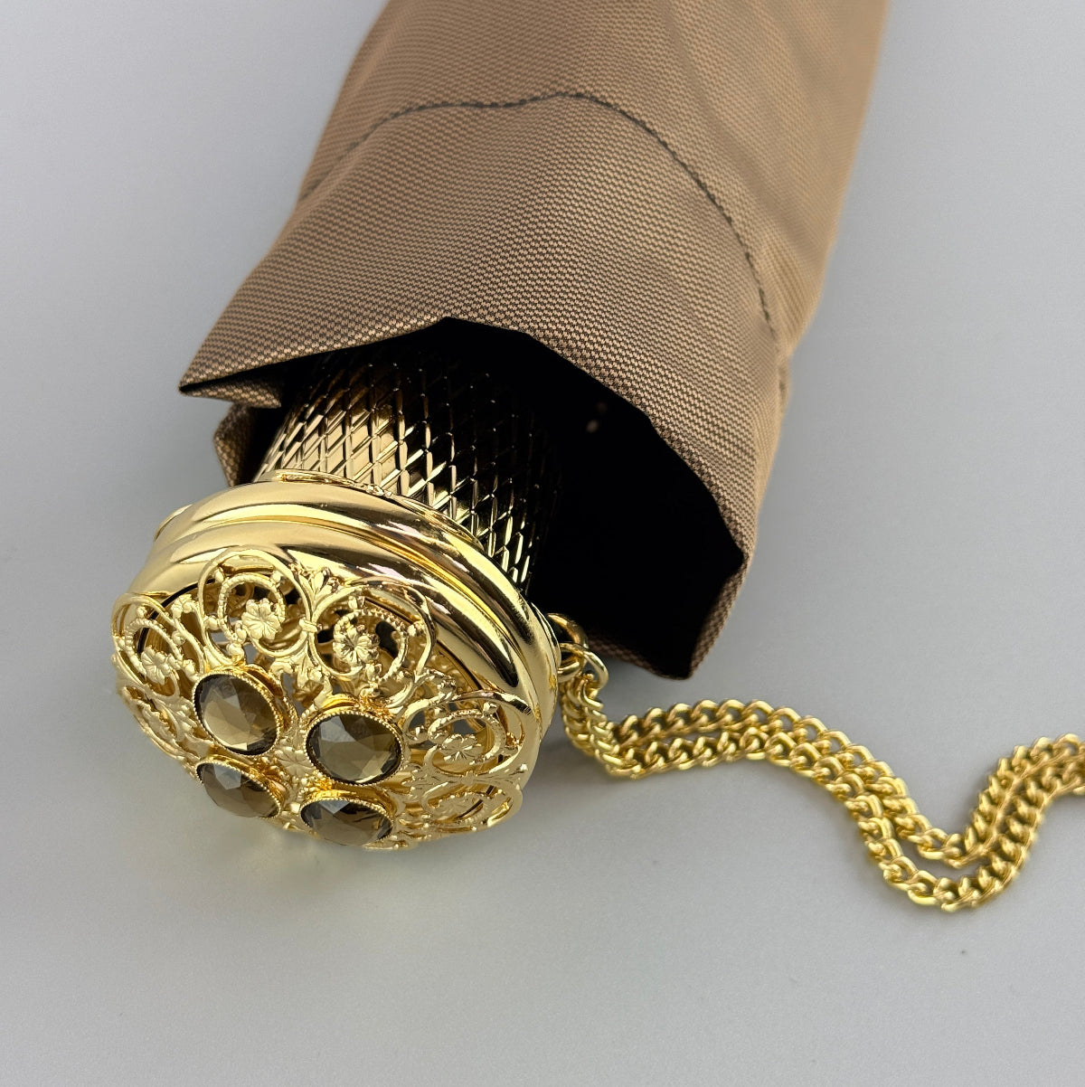 Pasotti foldable umbrella with decorative gold handle on a light gray background