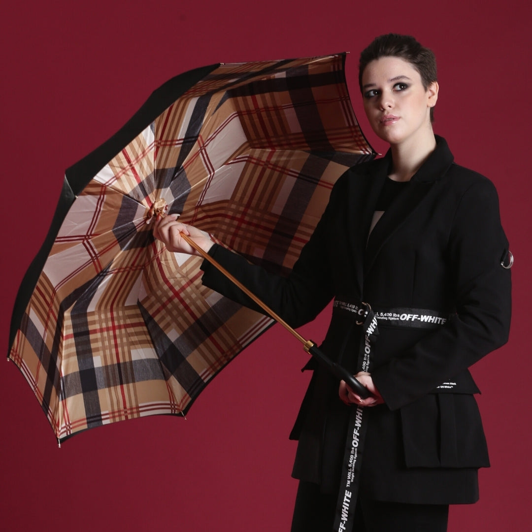 Person holding a plaid umbrella against a red background
