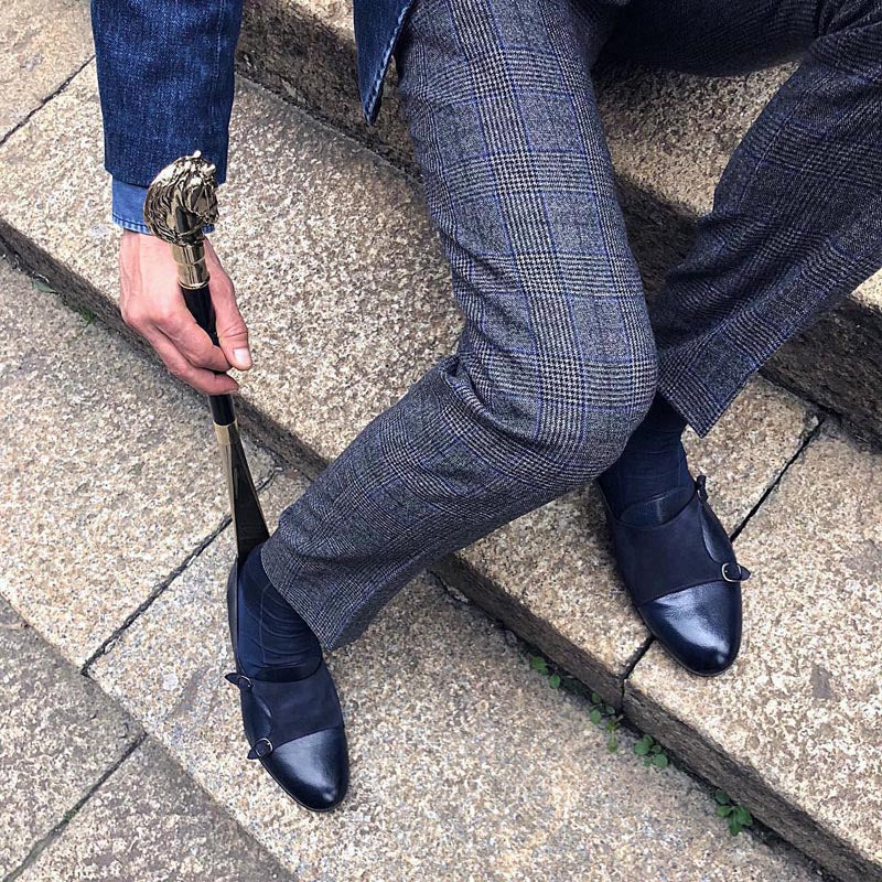 Lifestyle view of a man using the Pasotti CS W41 shoehorn with a silver-tone horse-head handle