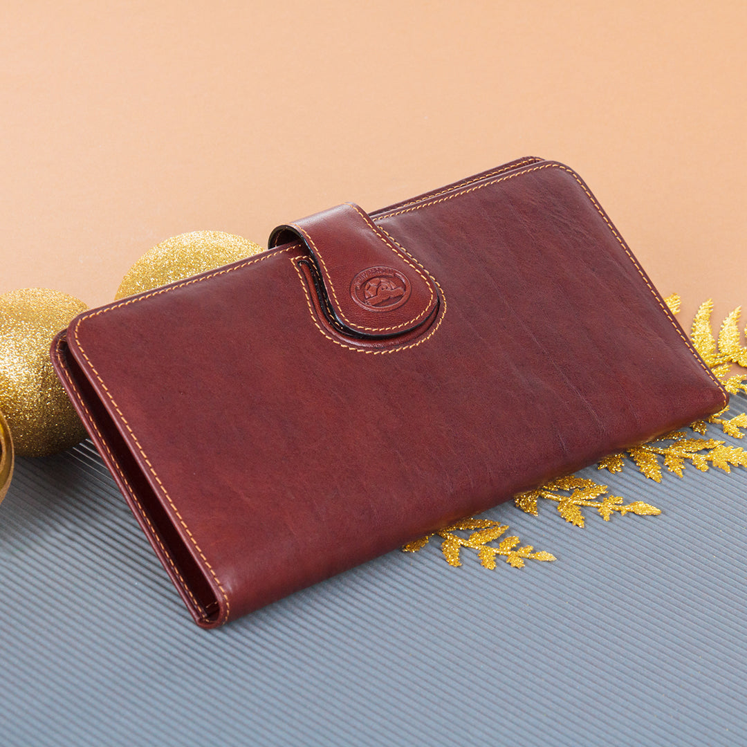 Tony Perotti brown leather travel wallet on a textured surface with decorative elements