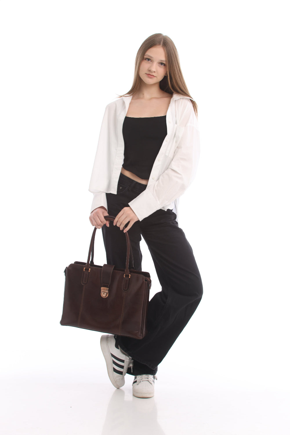 Woman in a white shirt and black jeans carrying the Tony Perotti Italico 9715-40 moro leather laptop bag by its handles, showing the size of the bag against a full-length figure