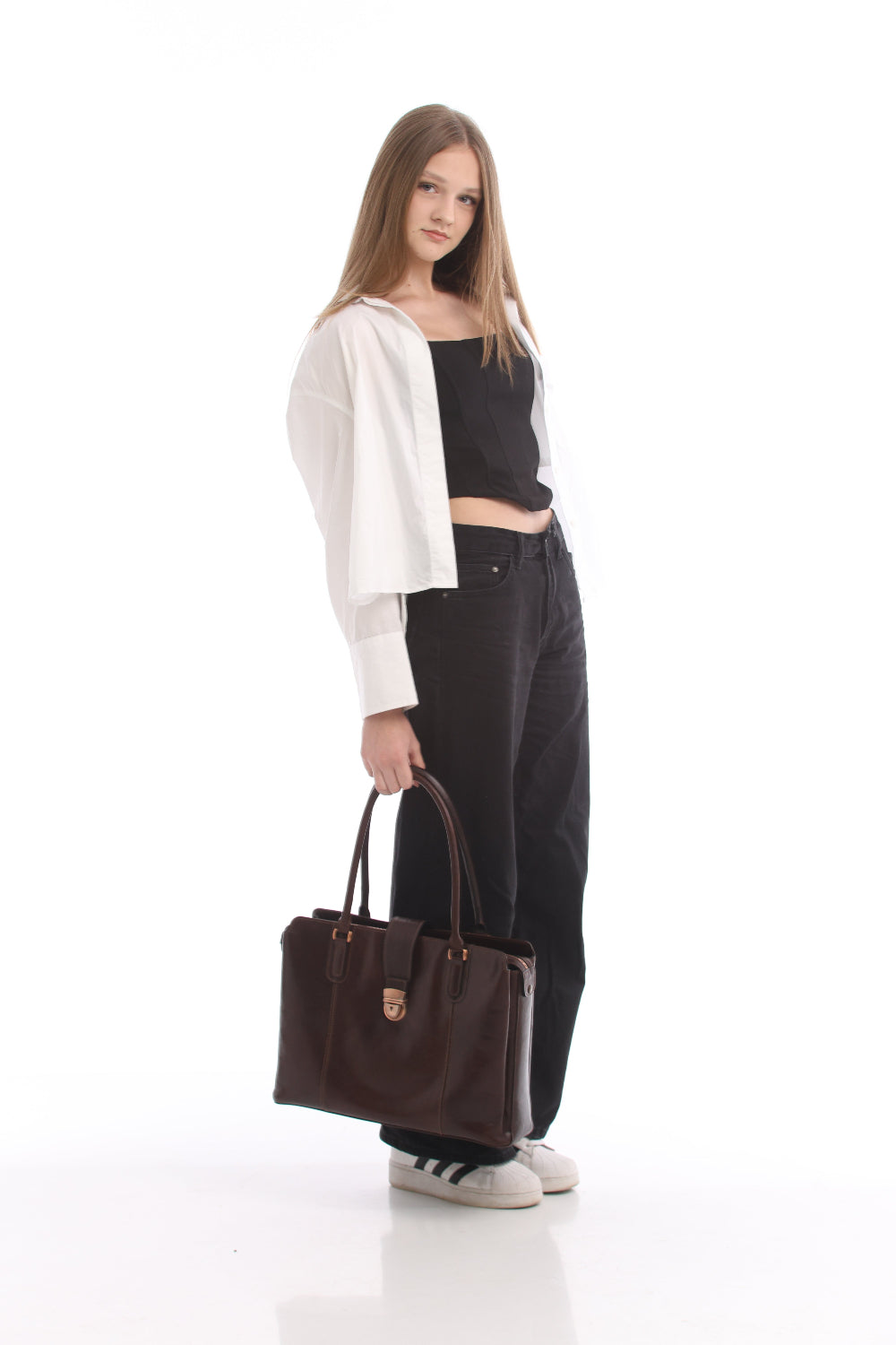 Woman standing side on with the Tony Perotti Italico 9715-40 moro leather laptop bag held at her side by the handles