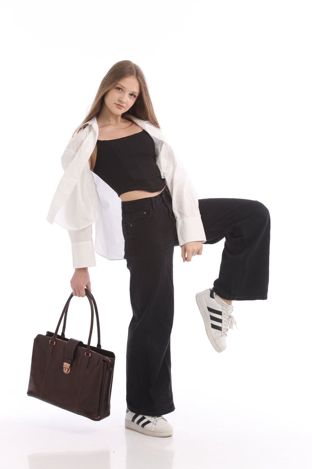 Woman carrying the Tony Perotti Italico 9715-40 moro dark brown leather laptop bag in one hand, the front strap and lock facing the camera