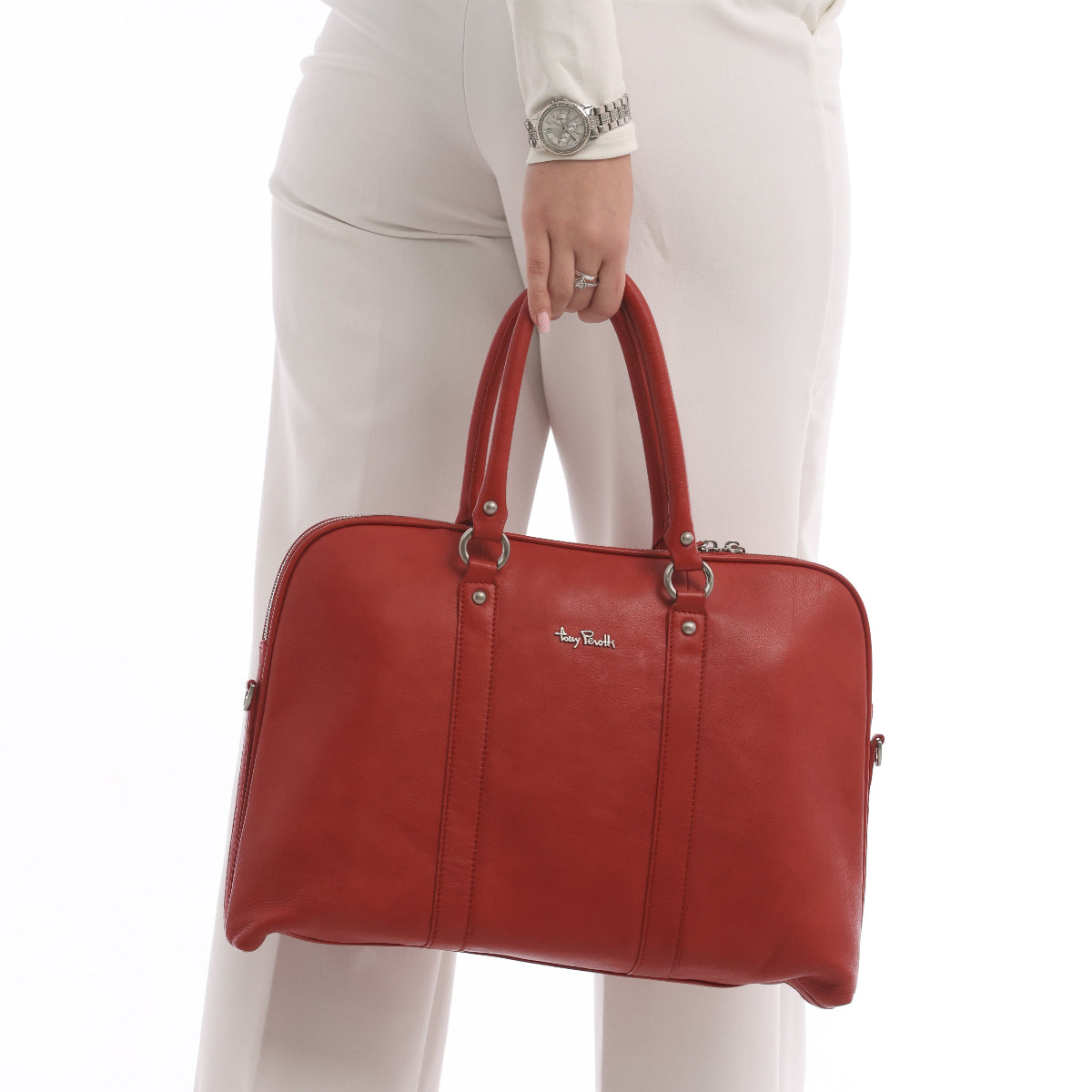 Close-up of the Contatto 9574-40 rosso briefcase in the hand: rolled handles, silver rings and the metal Tony Perotti script