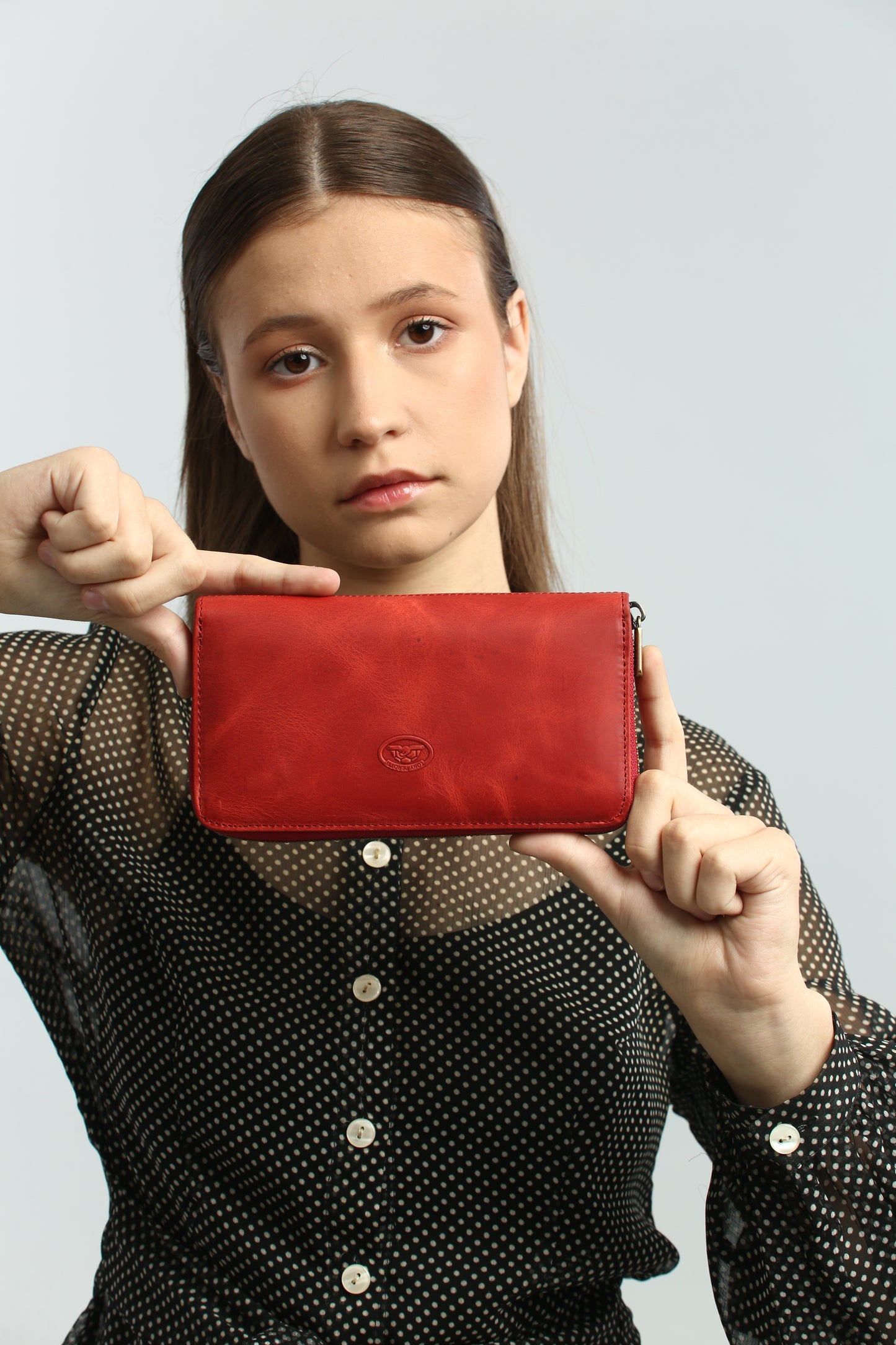 Person holding a Tony Perotti red vintage-look leather wallet against a plain background