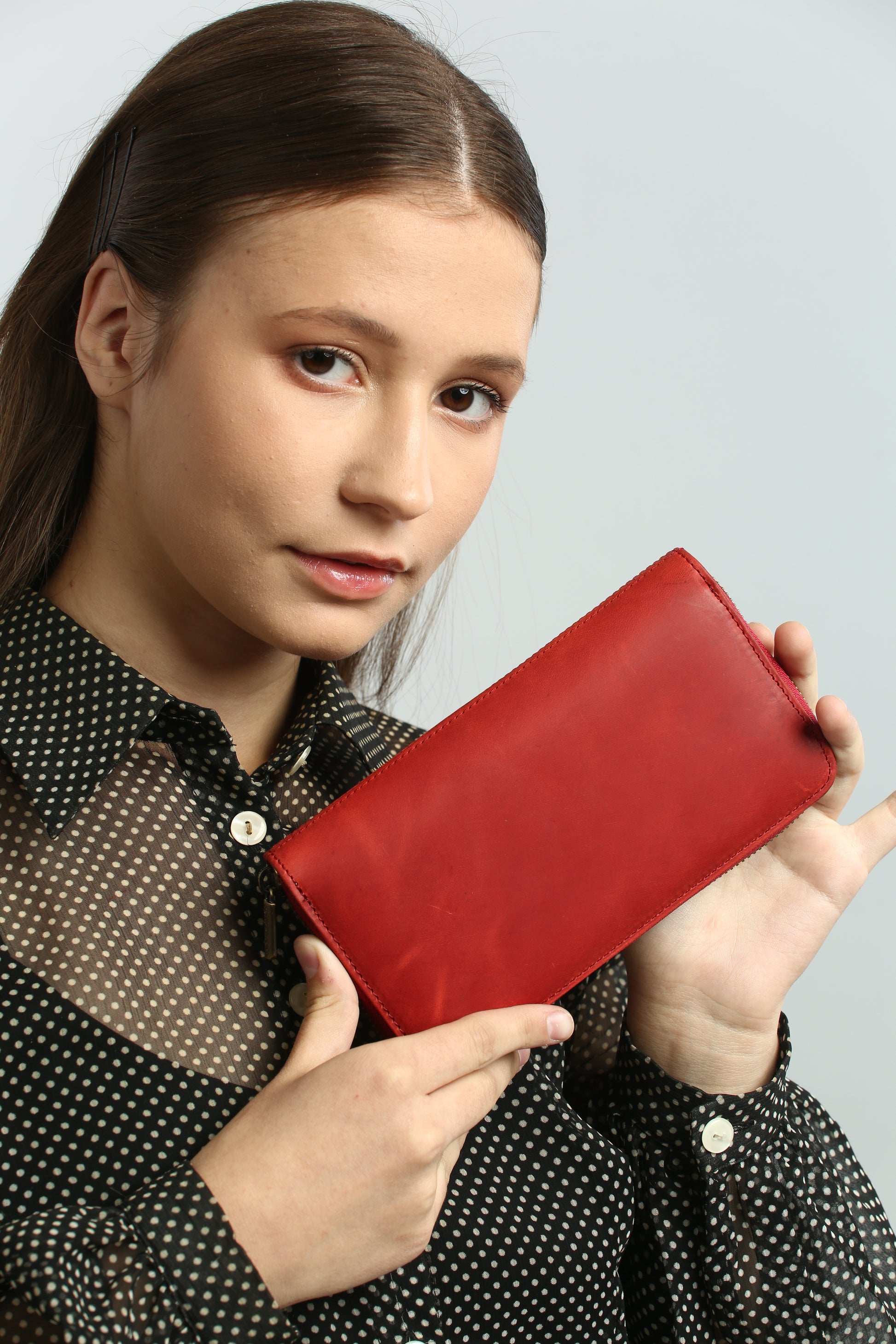 Woman holding a Tony Perotti red vintage-look leather wallet against a plain background