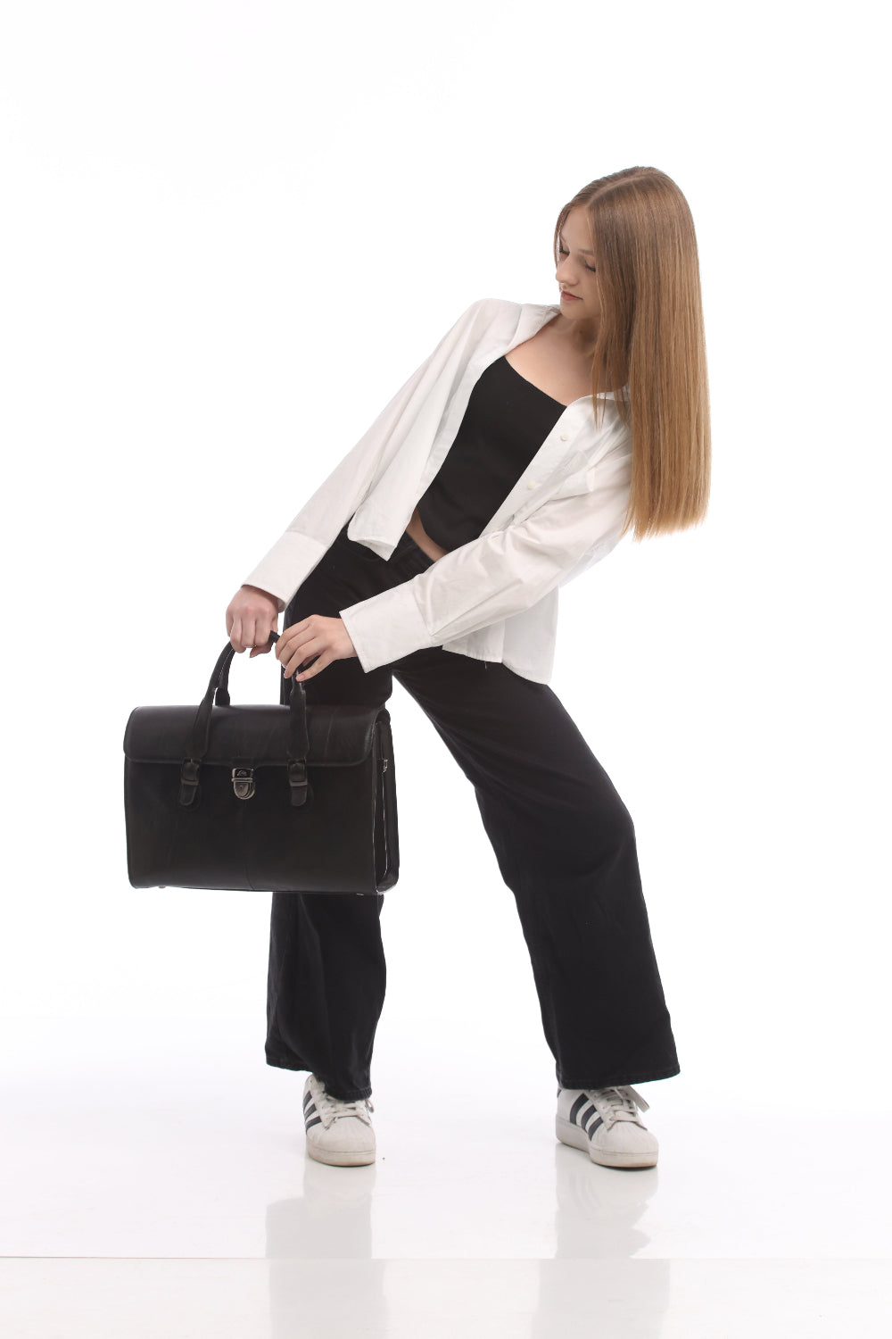 The Tony Perotti Italico 8965 briefcase carried in the hand — the flap, buckled straps and centre lock seen from the side