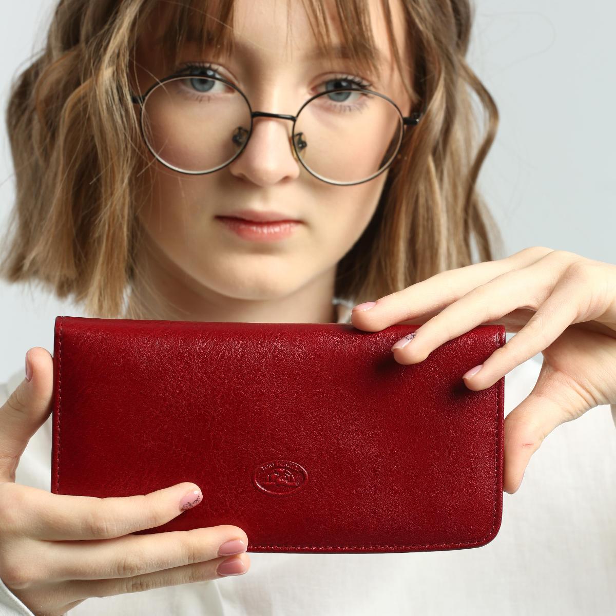 Person holding a red wallet with a plain background