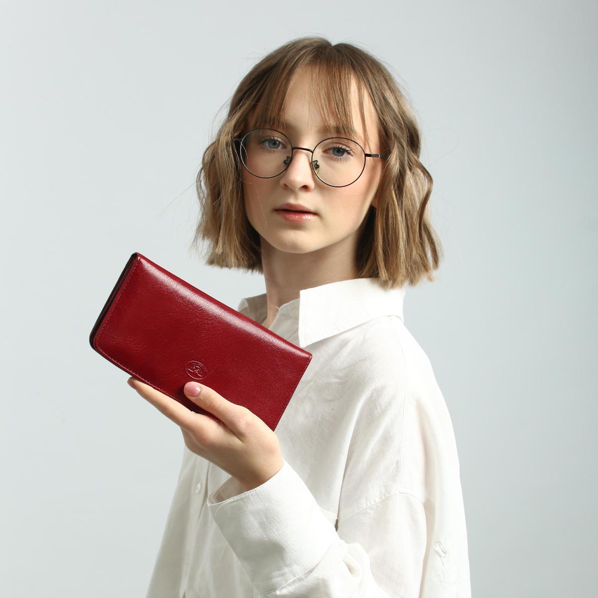 Person holding a red wallet against a plain background