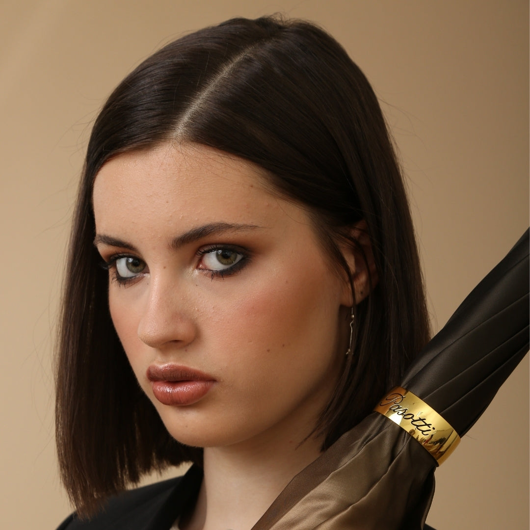 Woman holding Pasotti bronze striped cane umbrella in elegant neutral style