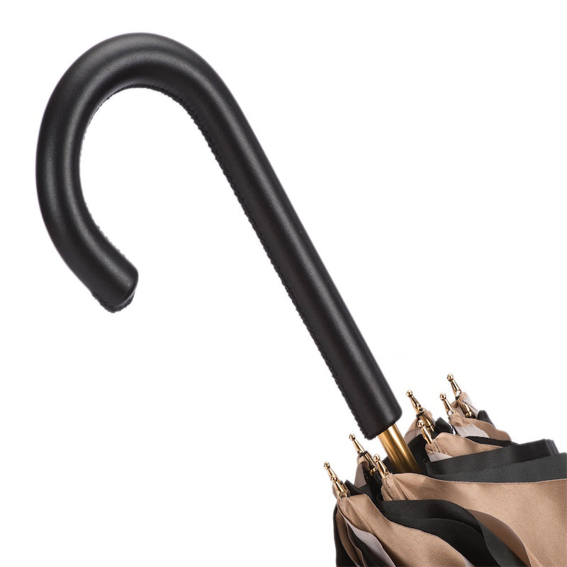 Close-up of a dark brown umbrella handle with gold tips on a white background