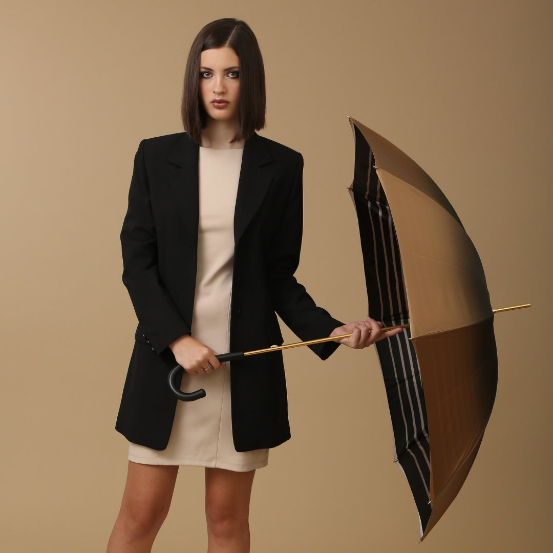 Woman holding an open umbrella against a beige background