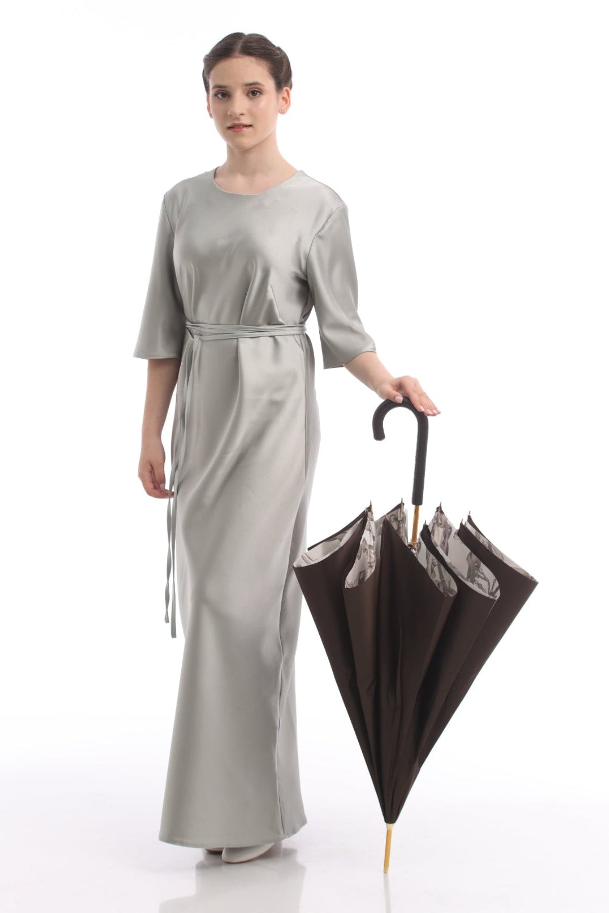 Model holding a closed Pasotti women’s brown cane umbrella with equestrian-print interior