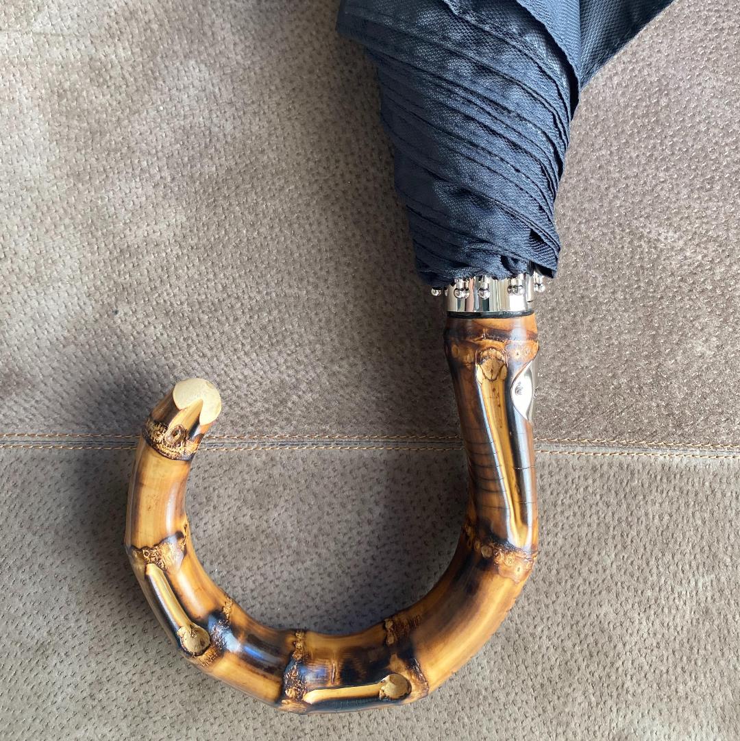 Men’s black folding umbrella by Pasotti held by bamboo handle