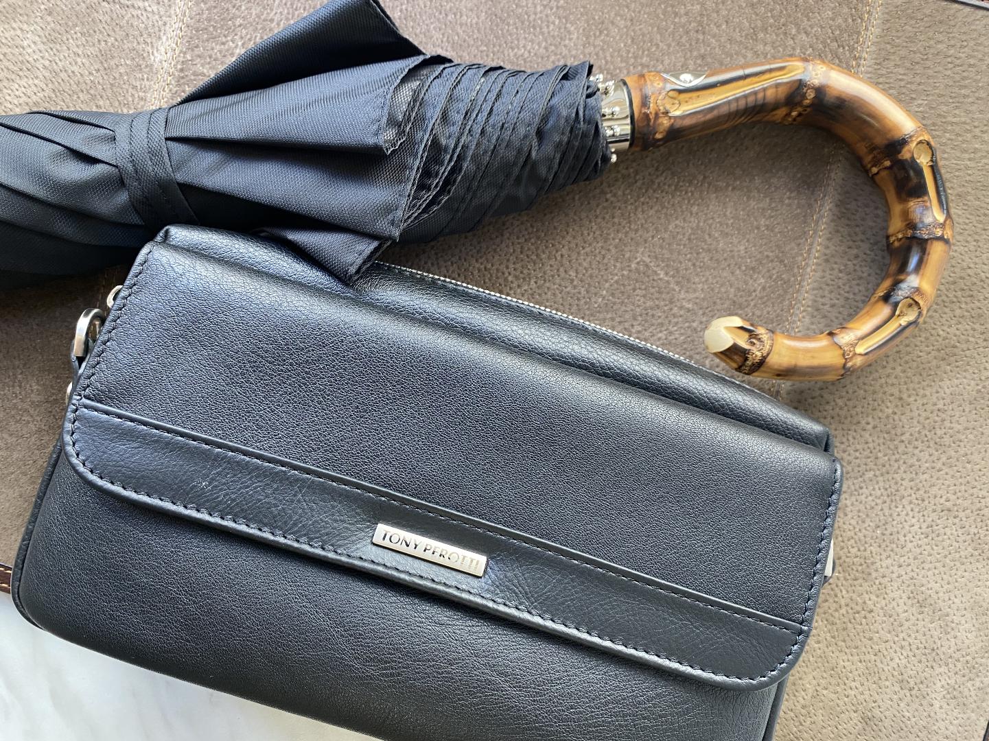 Men’s Pasotti folding umbrella with bamboo handle next to leather bag