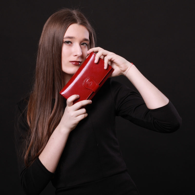Woman holding a red wallet against a black background