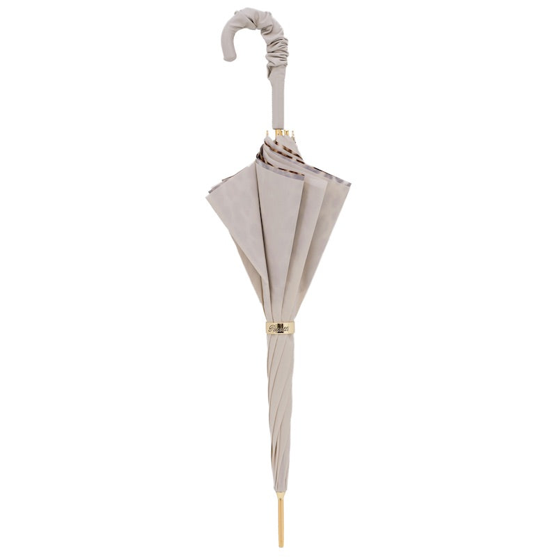 Closed ivory umbrella standing upright with the ruched leather crook handle and gold-tone ring
