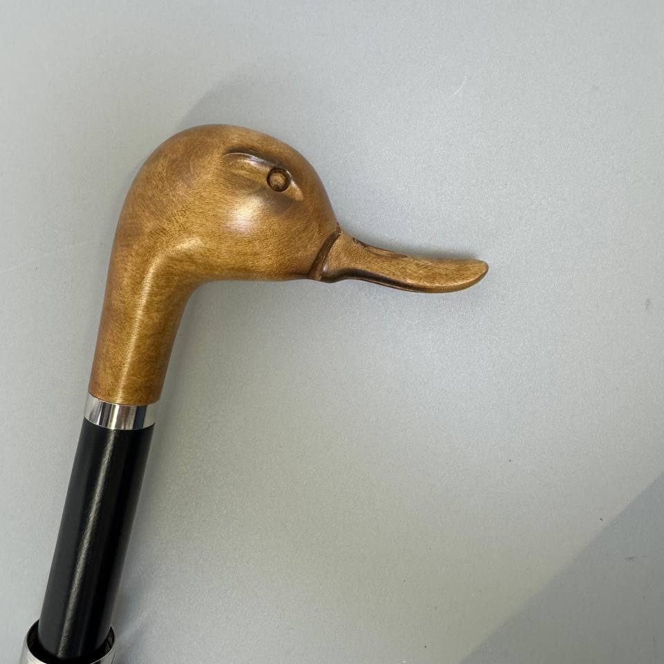 Honey-toned duck head handle in profile on a grey background