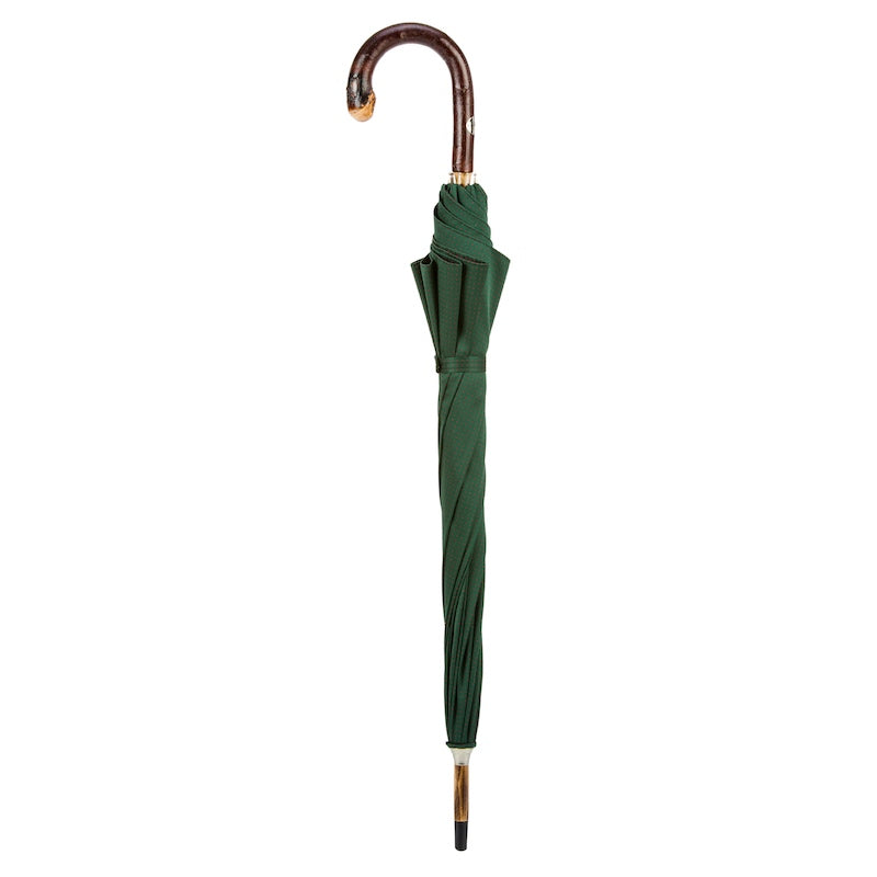 Closed dark green umbrella standing upright with chestnut crook handle