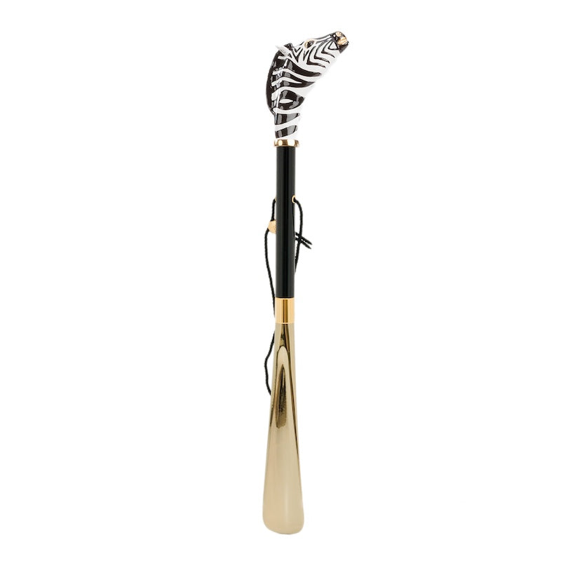 Zebra shoehorn standing upright: glossy black shaft, hanging cord and gold-tone blade
