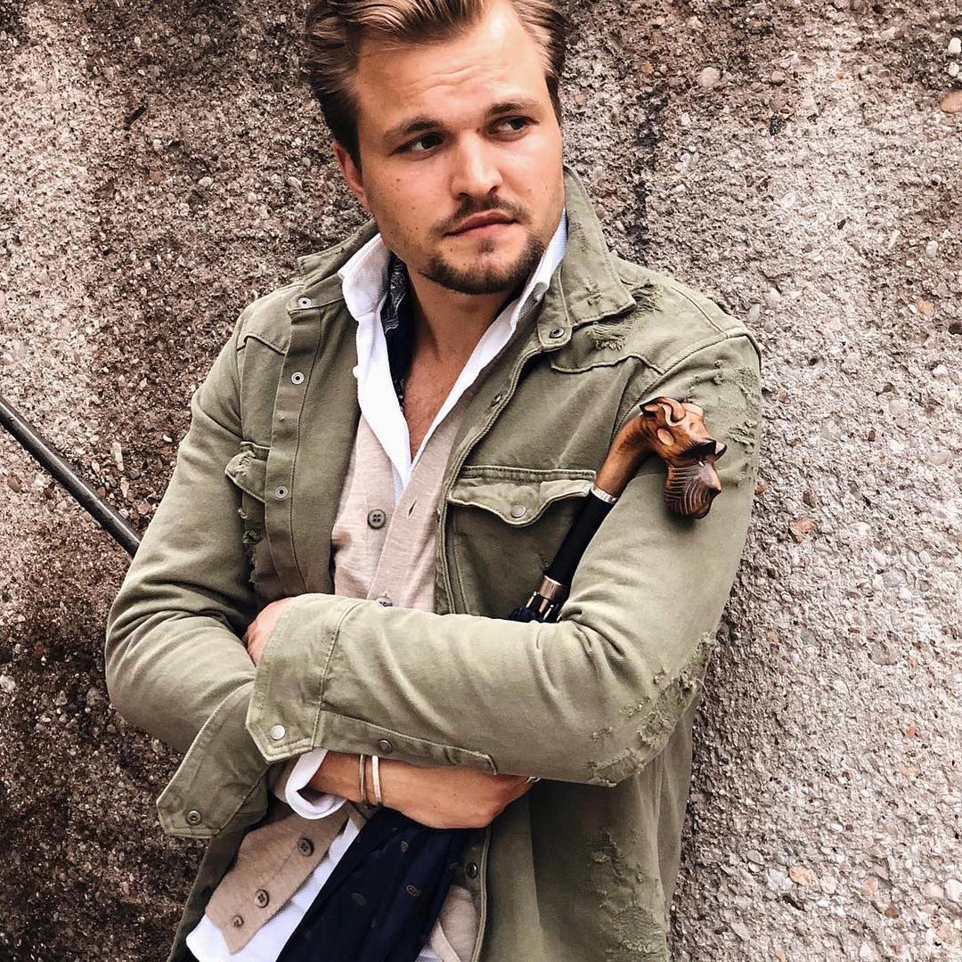 Man in an olive jacket with the furled umbrella and its carved schnauzer handle