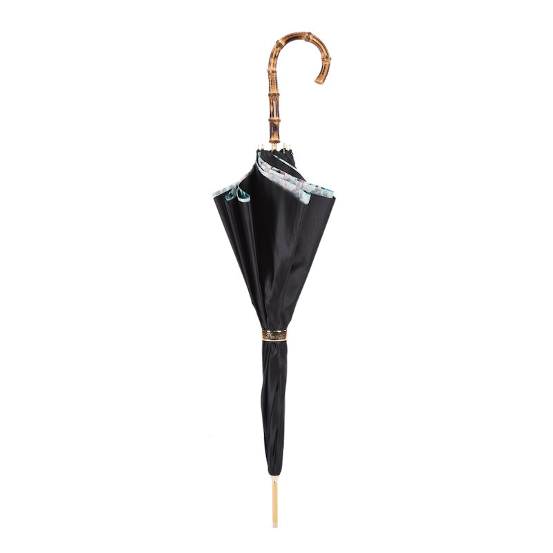 Closed black umbrella standing upright with the bamboo crook handle and gold-tone ring