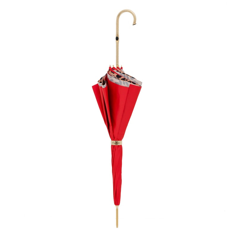 Closed red umbrella standing upright with the gold-tone brass crook handle and ring
