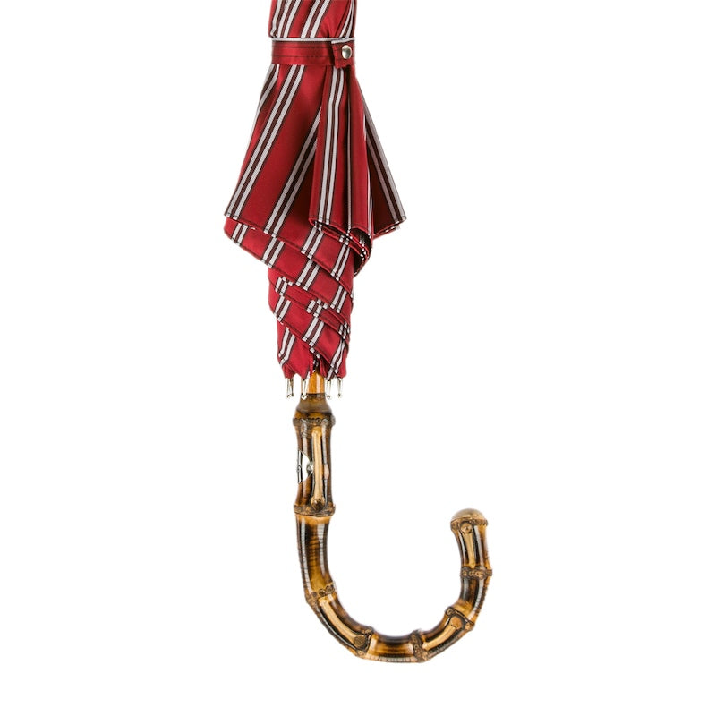 Furled red striped canopy with matching strap above the bamboo crook handle