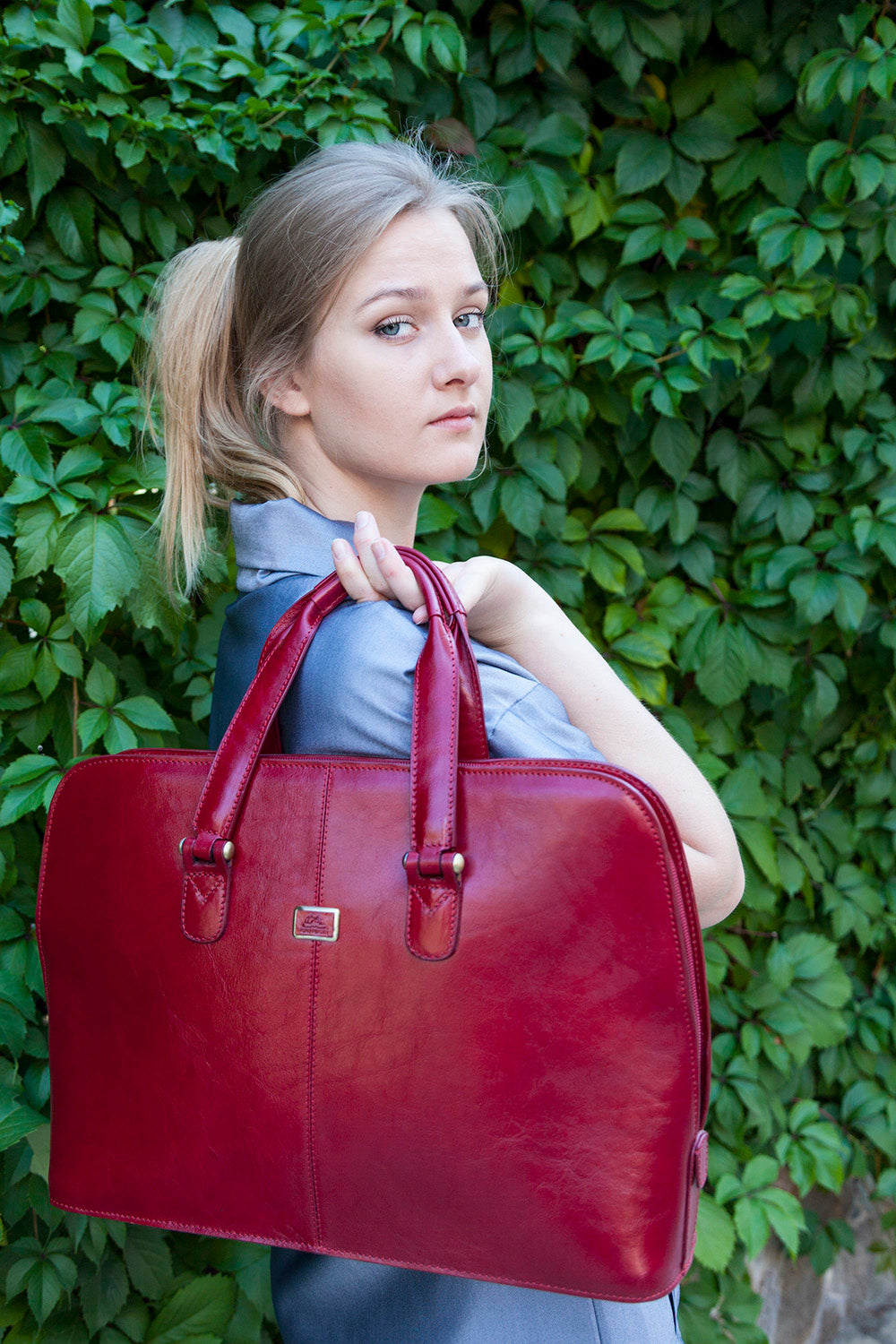 Woman carrying the red Tony Perotti Italico 8149 leather business bag by its handles over the shoulder