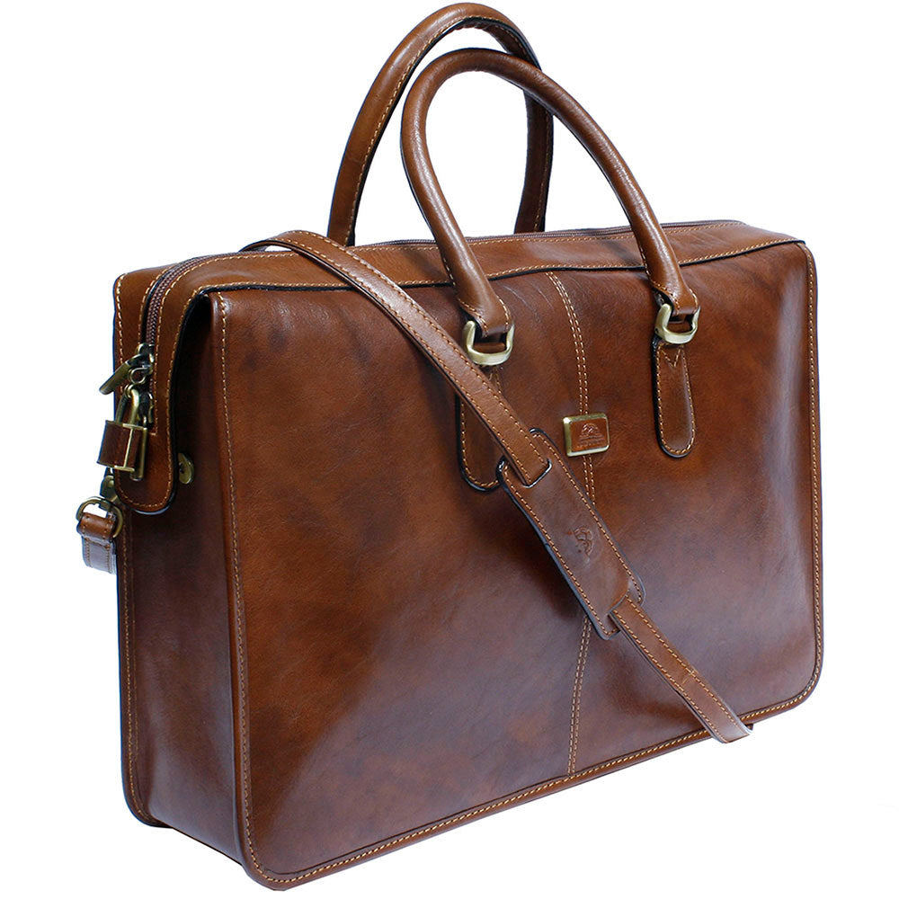 Three-quarter view of the Tony Perotti Italico 8098 cognac briefcase with the detachable leather shoulder strap and the small padlock on the zip