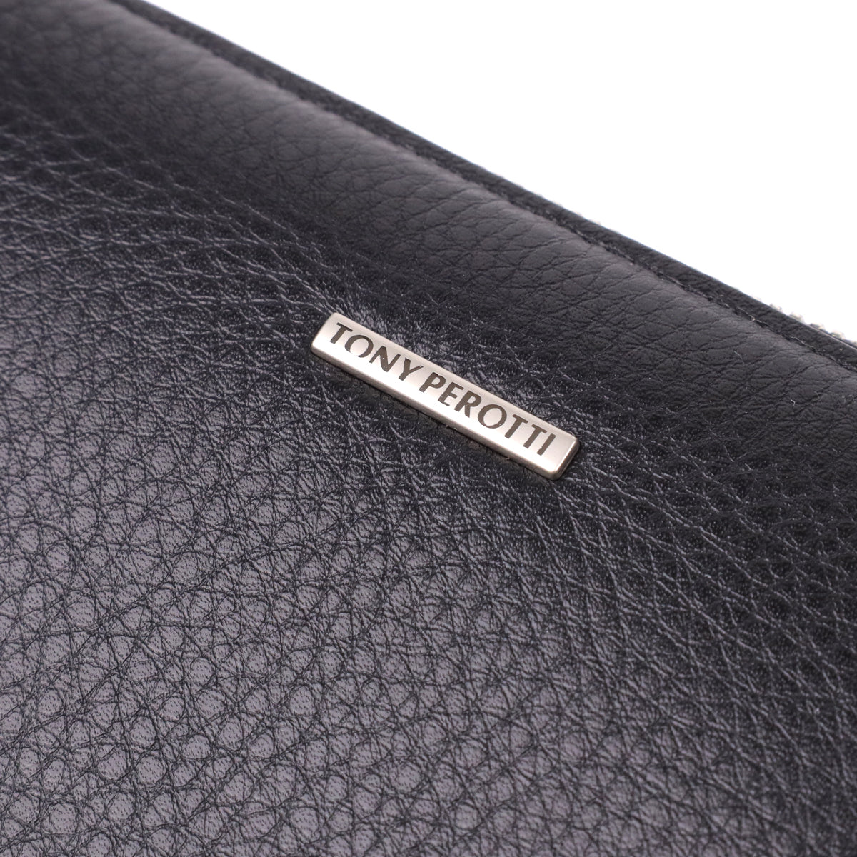 Close-up of the metal TONY PEROTTI plate on the pebble-grain calf leather of the New Contatto 2651 nero
