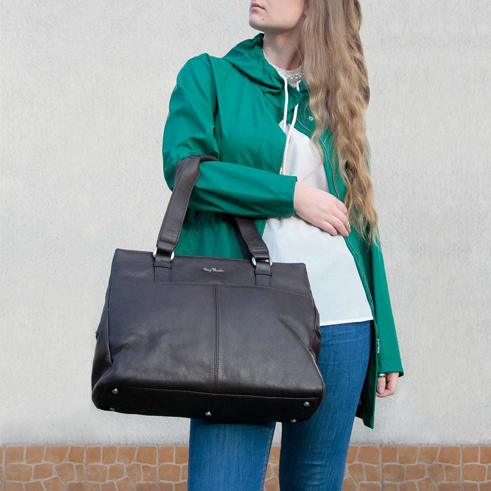 Woman carrying the dark brown Tony Perotti Contatto 9716 moro tote bag over her arm — the metal feet on the base and the Tony Perotti signature on the front panel visible