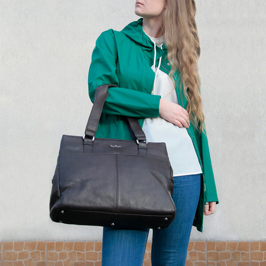 Woman carrying the dark brown Tony Perotti Contatto 9716 moro tote bag over her arm — the metal feet on the base and the Tony Perotti signature on the front panel visible