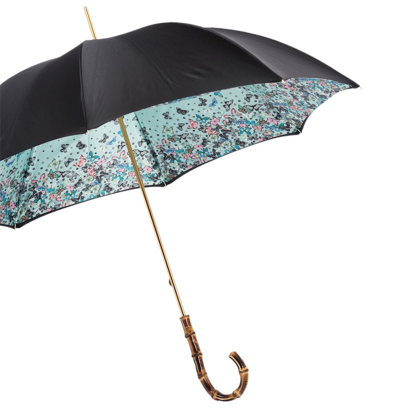 Open black umbrella from the side showing the butterfly print inside the canopy and gold-tone shaft