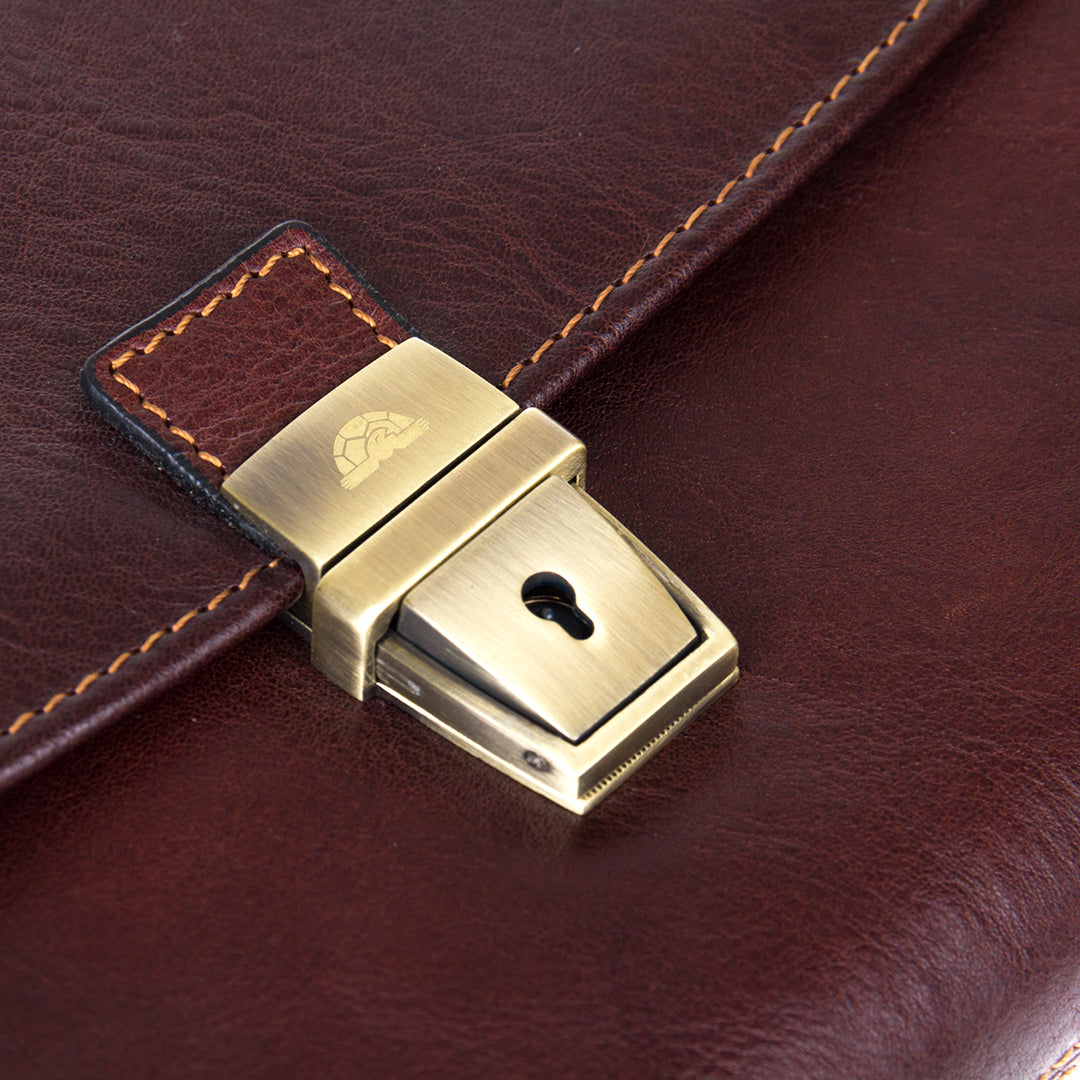 Close-up of the antique brass clasp lock of the Italico 9337 — engraved turtle emblem and keyhole